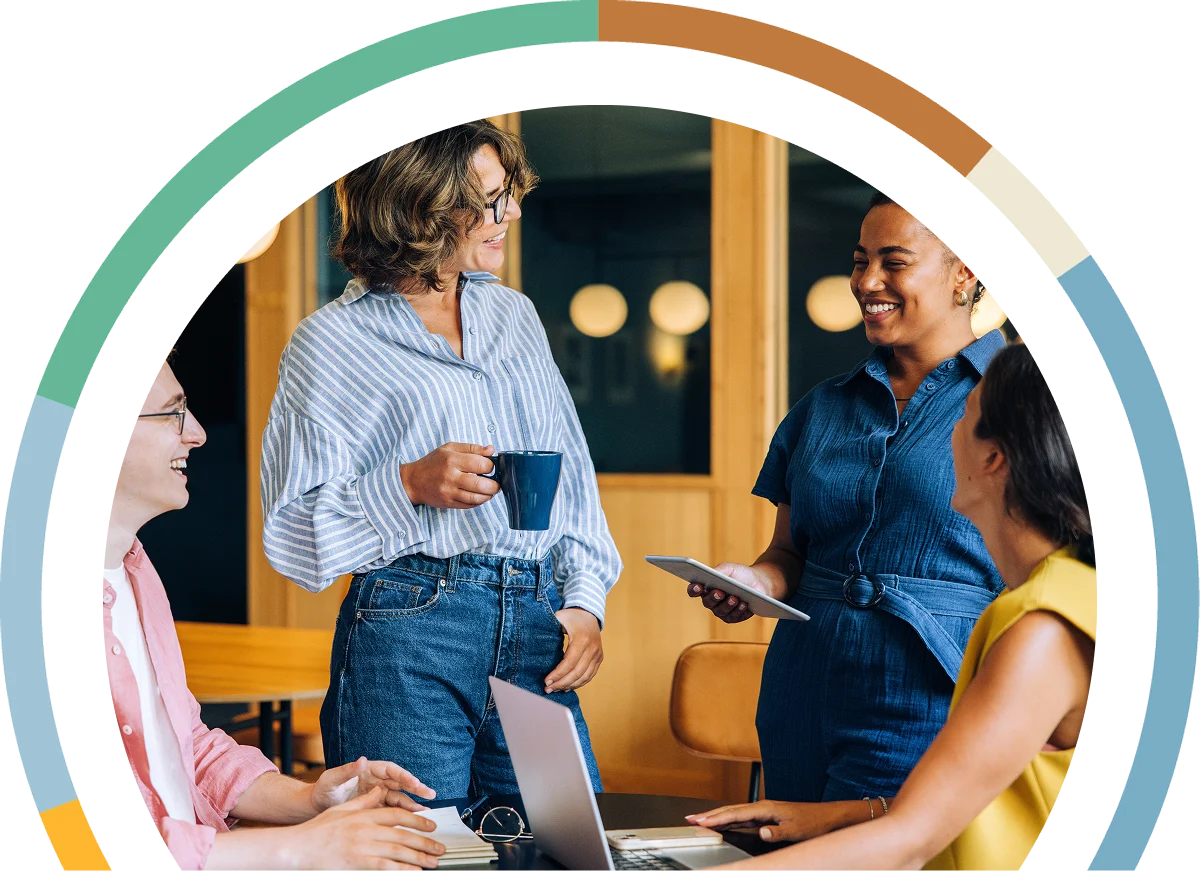 Young people standing around a desk smiling and discussing data