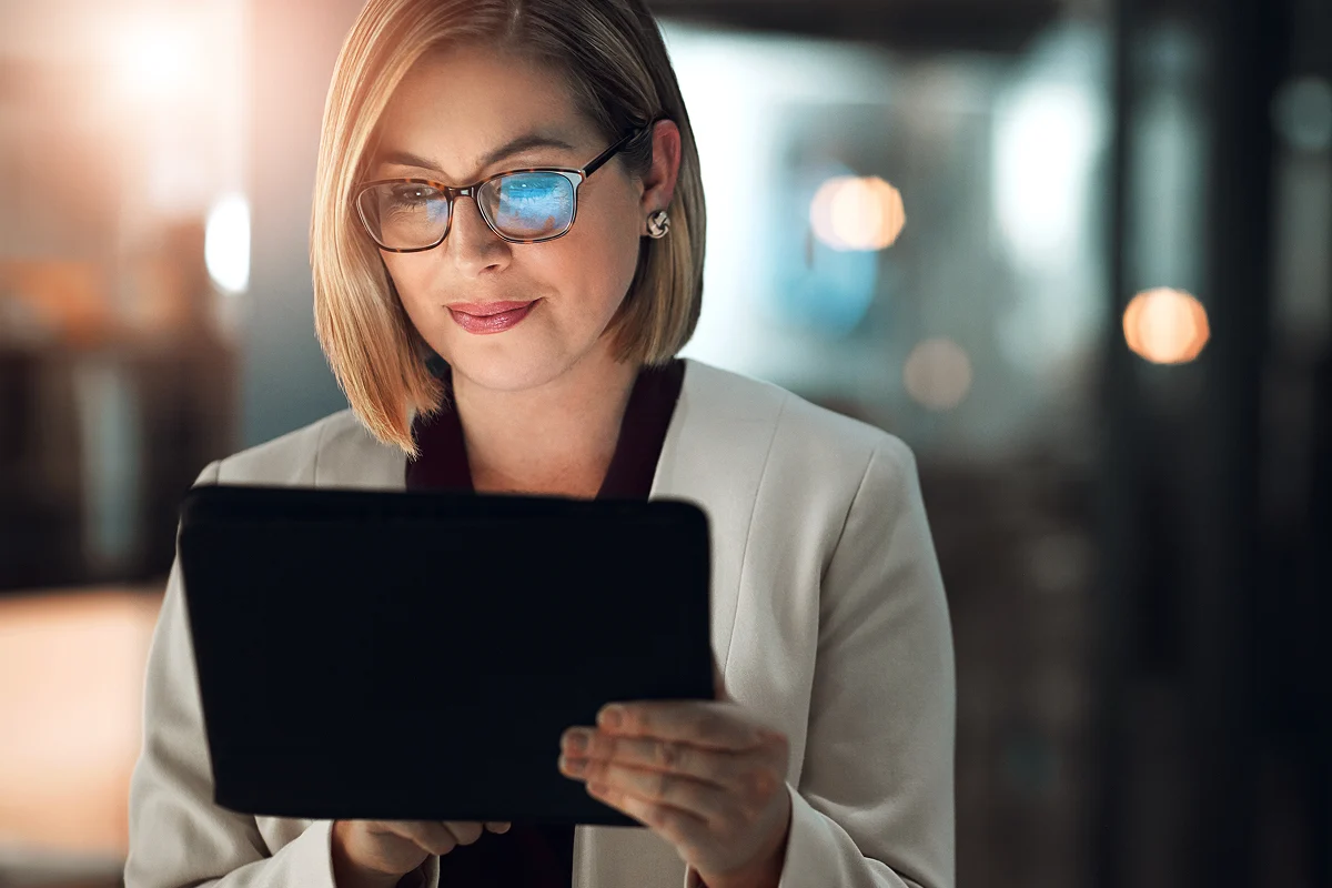 Business woman looking at data on an ipad with blurred, bright lights in the background
