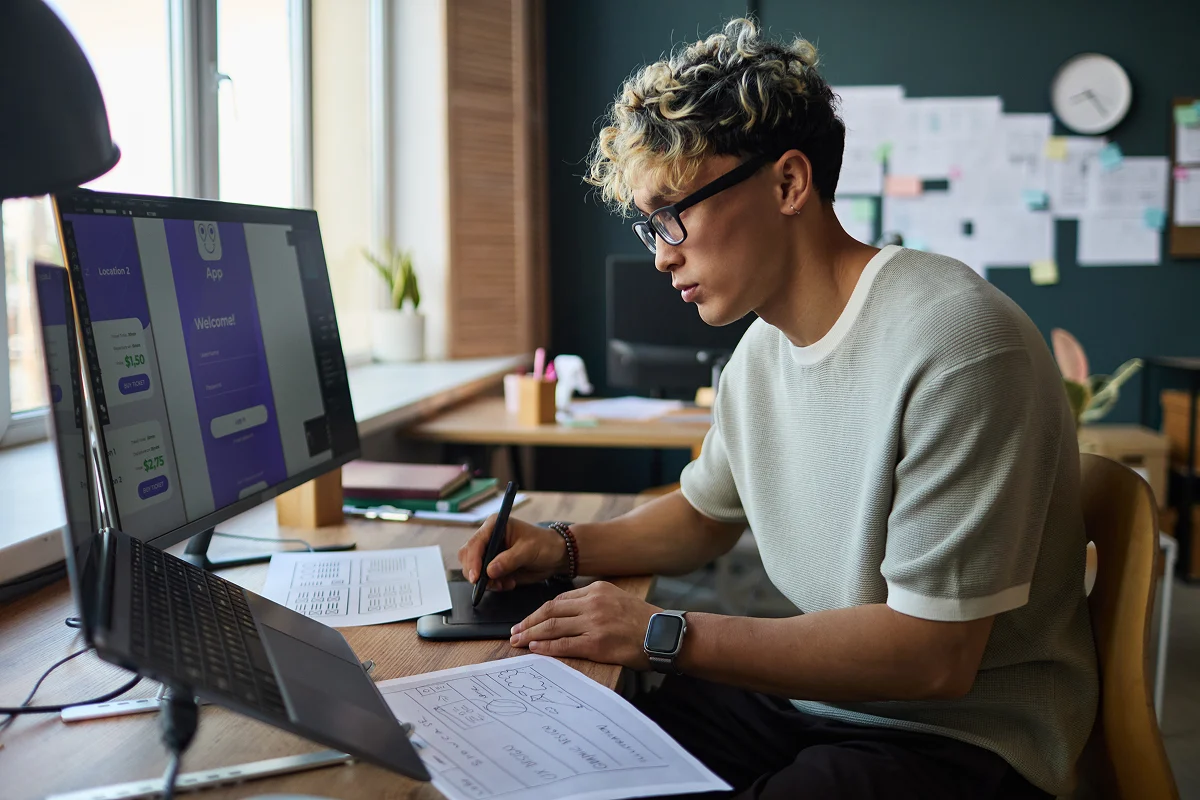 Young person seated at a desk, working on design software on a computer